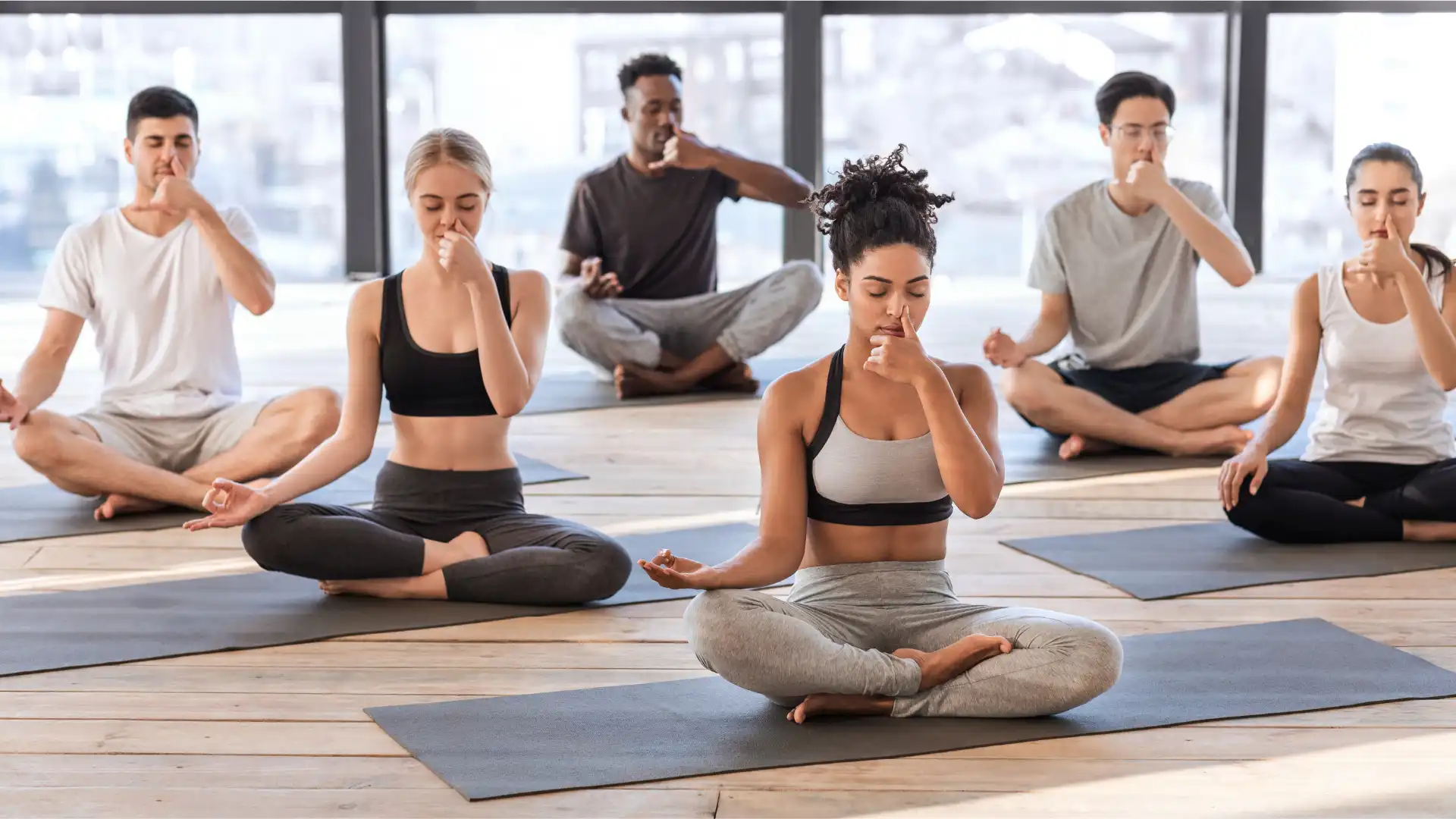 Yoga class practicing Alternate Nostril Breathing (Nadi Shodhana) to lower stress and create a peaceful and present practice