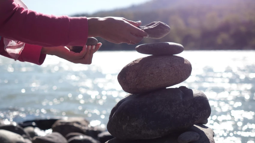 pebble stack next to the mountain river symbolic of slowing down and enjoying the awe of nature