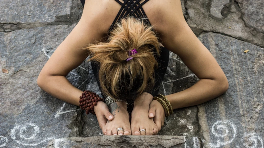 Yoga student in forward fold which is representative of folding inward to examine one's true nature