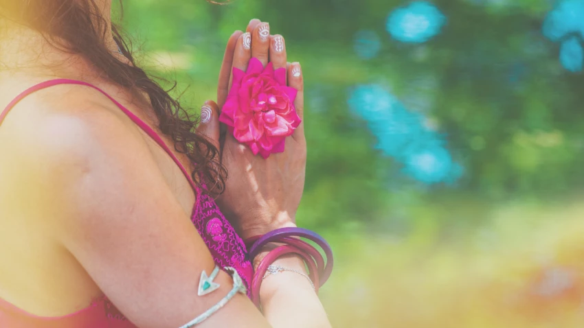 Close up of yoga woman hands in namaste gesture with rose flower outdoor summer day light leak