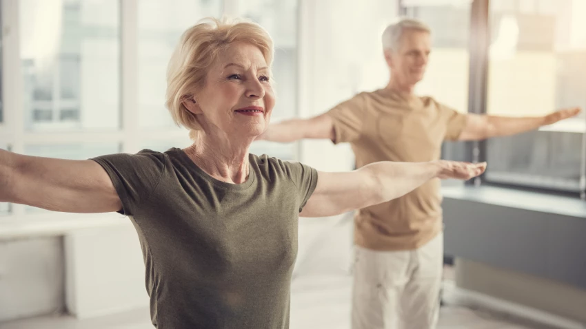 Older woman with arms straightened out to the side in yoga class