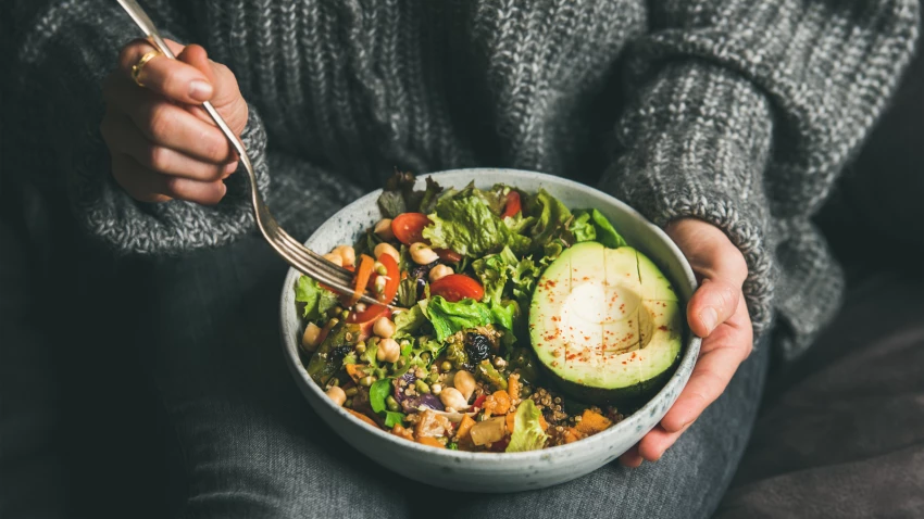 woman having a healthy high-fiber dinner of fresh salad, avocado, grains, beans, roasted vegetables