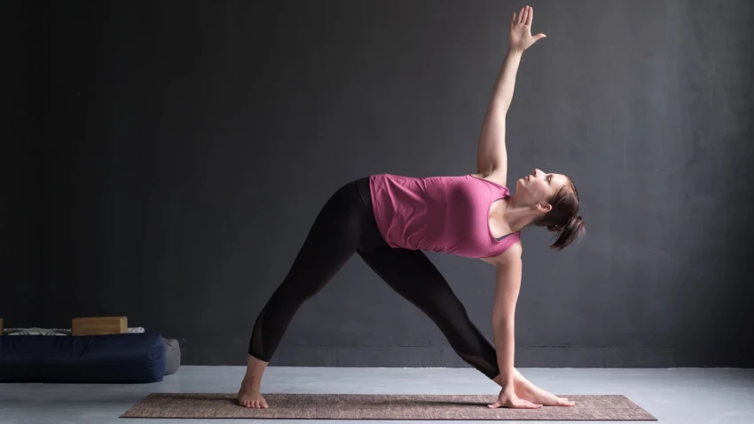 Woman practicing yoga balancing on one leg on a mat in a high key