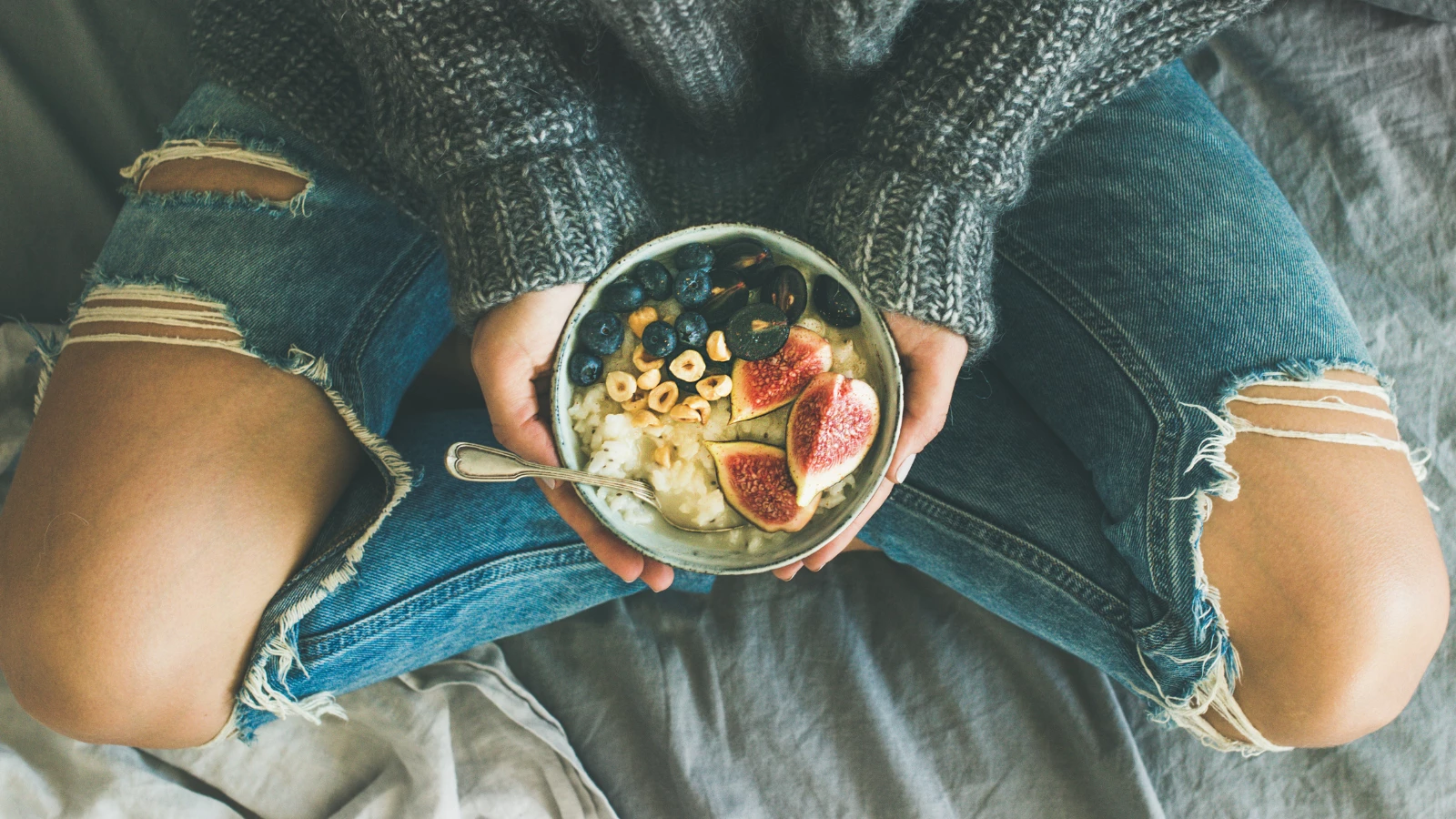 woman eating healthy plant-based diet with rice coconut porridge with figs, berries, hazelnut