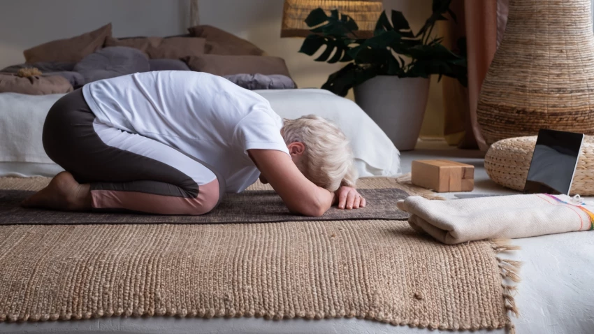 Senior woman doing forward bend yoga exercise Balasana, Child Pose