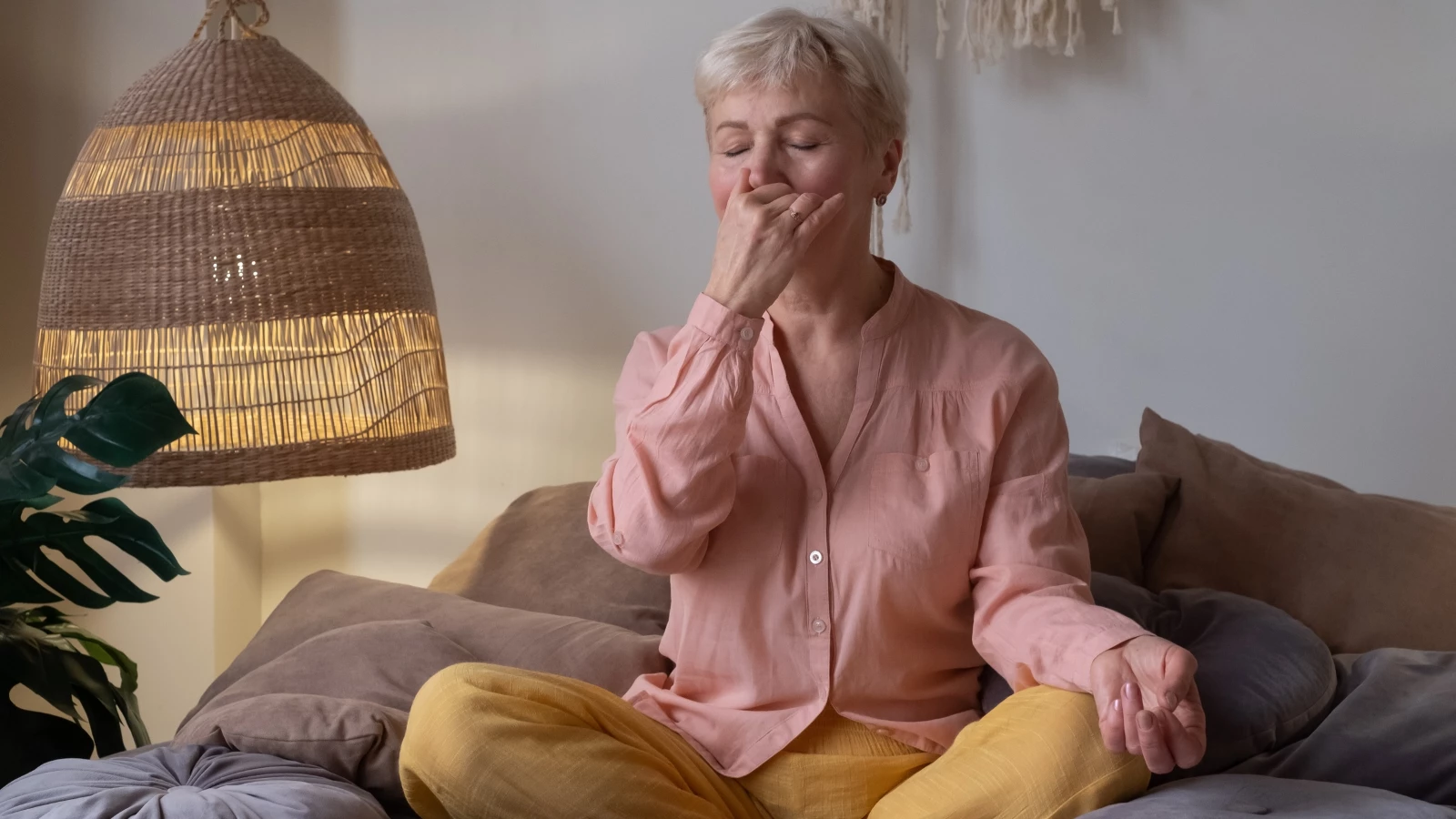 Senior woman practicing yoga at home, making Alternate Nostril Breathing or nadi shodhana