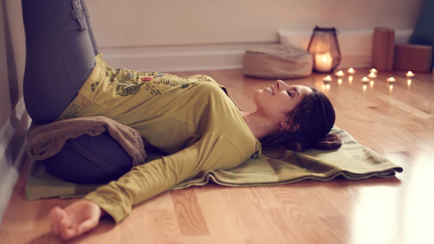 Serene lady relaxing and meditating on a yoga mat in a cozy house