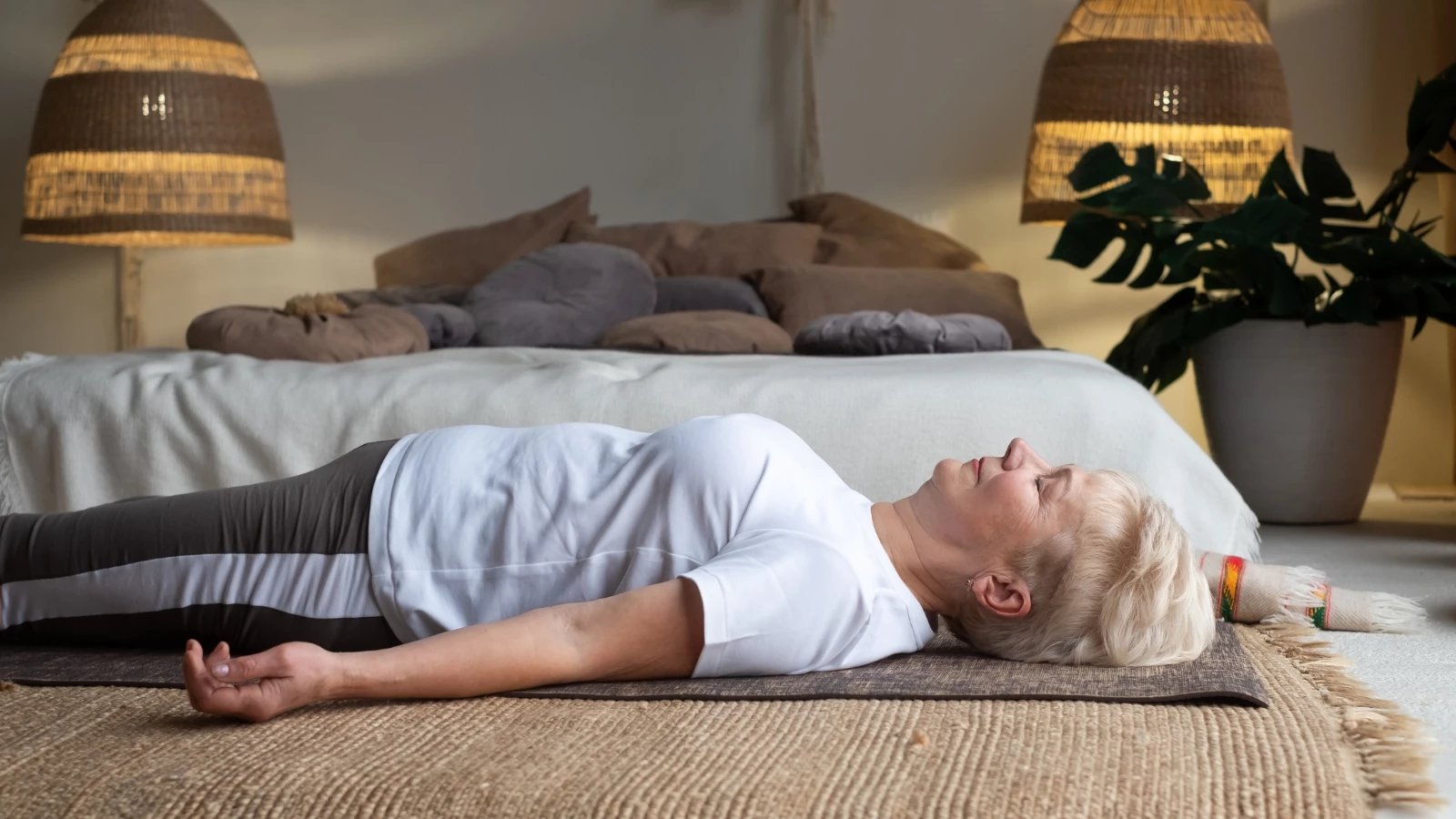 Senior woman lying on yoga mat practicing Savasana