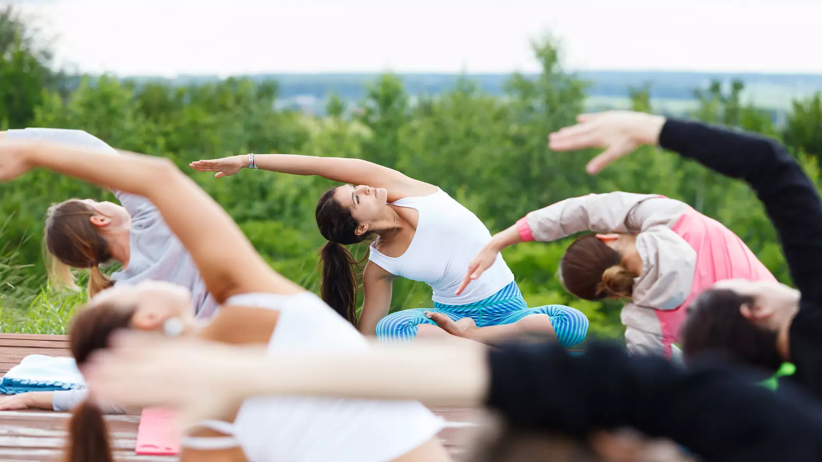 Group of people of different ages practicing yoga in the park.