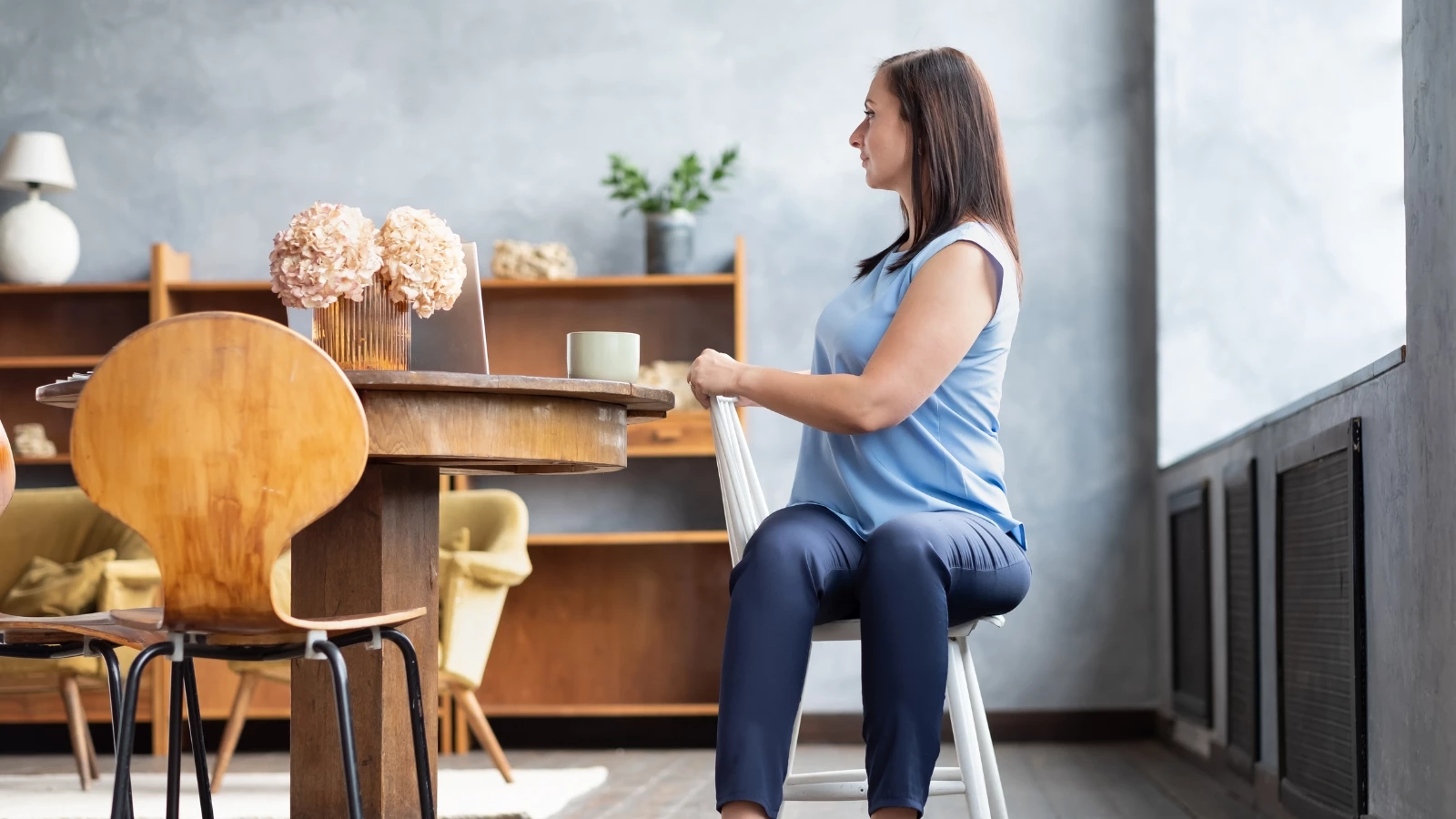 woman office worker in yoga pose variation Half Lord of the Fishes, Half Spinal Twist Pose sitting on a chair