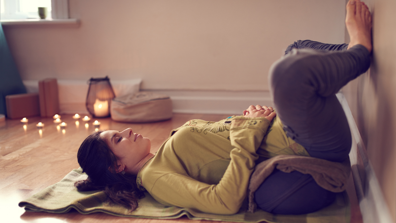 Serene lady relaxing and meditating on a yoga mat in a cozy house.