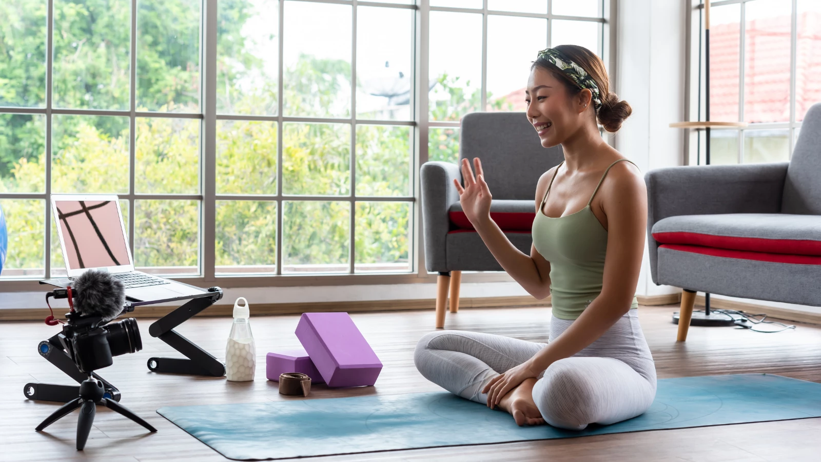 Young yoga teacher recording video content for her online course with camera and laptop.