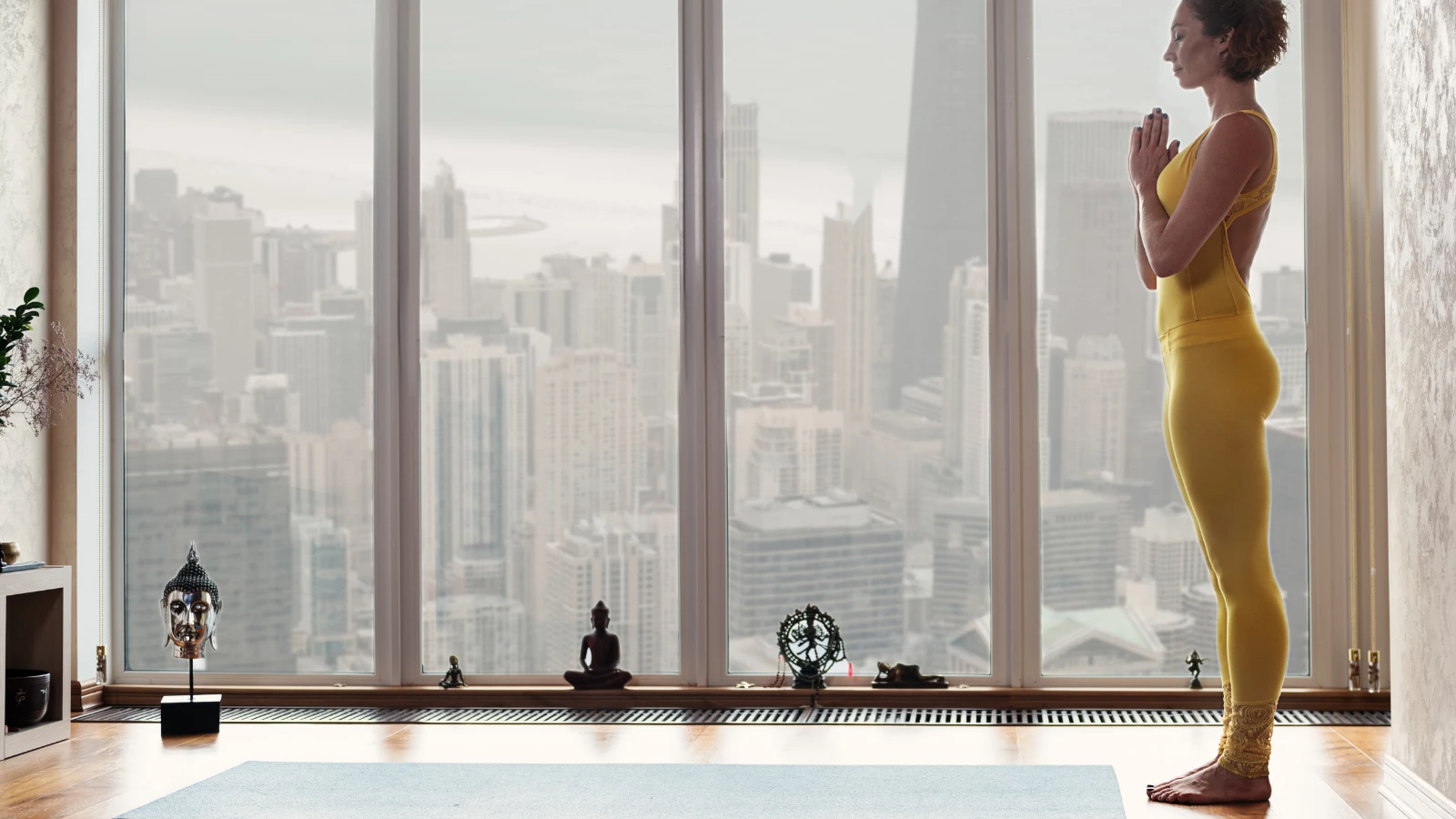 woman standing on a yoga mat and joining her hands together in Anjali Mudra (Hands to heart)