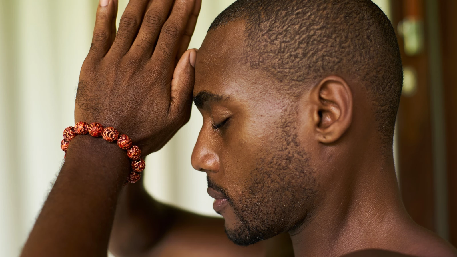 Portrait of an African American male with praying hands or Anjali Mudra to his forehead