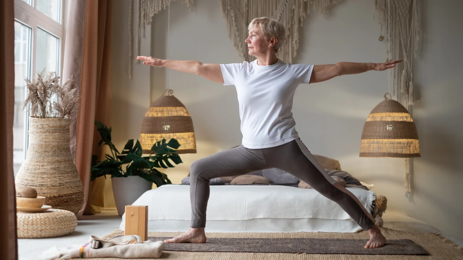 Senior woman practicing yoga, standing in Warrior II Pose.