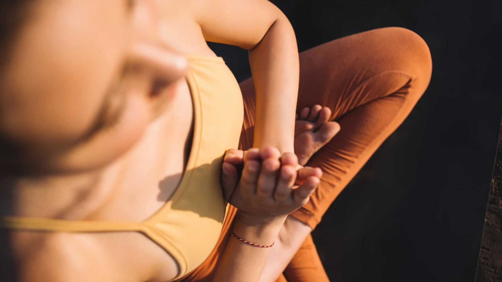 Cropped image of young woman in activewear sitting in Lotus Pose keeping hands in namaste for relaxing meditation