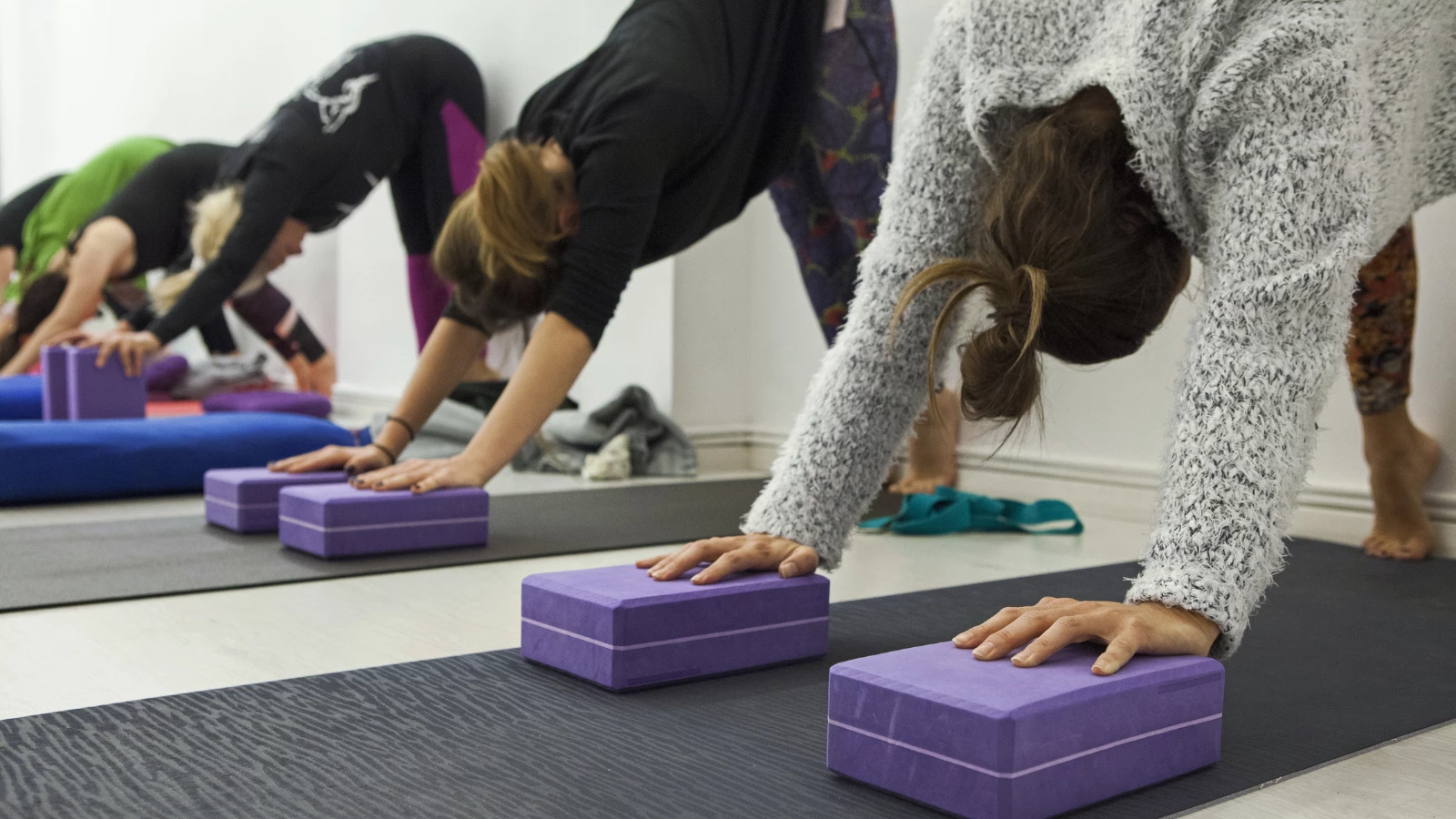 Women practicing yoga therapy, stretching in Down Dog using blocks and the wall