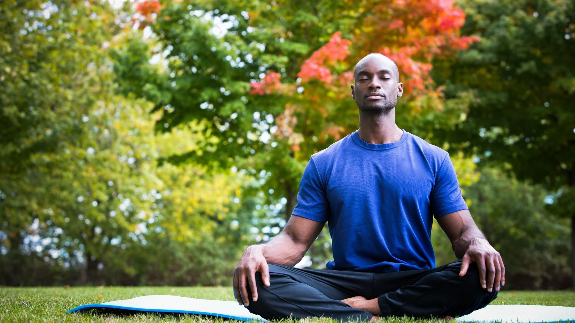 African-American Yogi sitting in Lotus Pose and meditation with closed eyes at an outdoor nature set