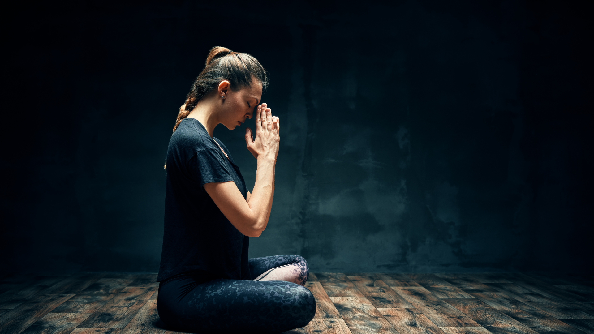 Rear view of young woman practicing yoga sitting in Lotus pose with namaste copy space.