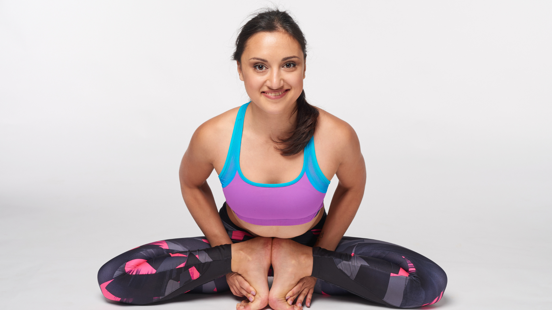 Young attractive woman practicing yoga doing Mulabandhasana, The Root Lock Pose in full length, isolated over white studio background.