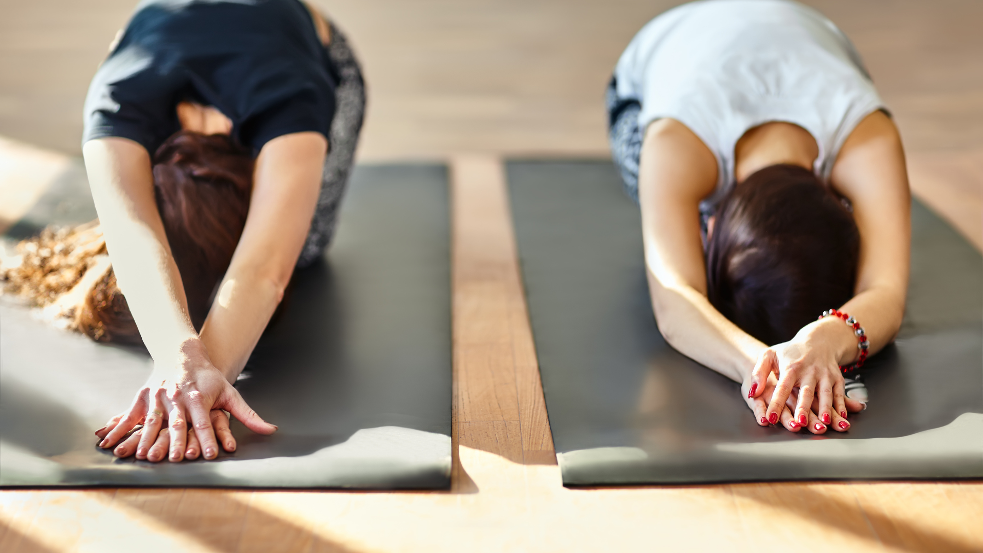 Two young women doing yoga asana Child’s Pose or Balasana in a yoga practice that draws on Internal Family Systems Therapy