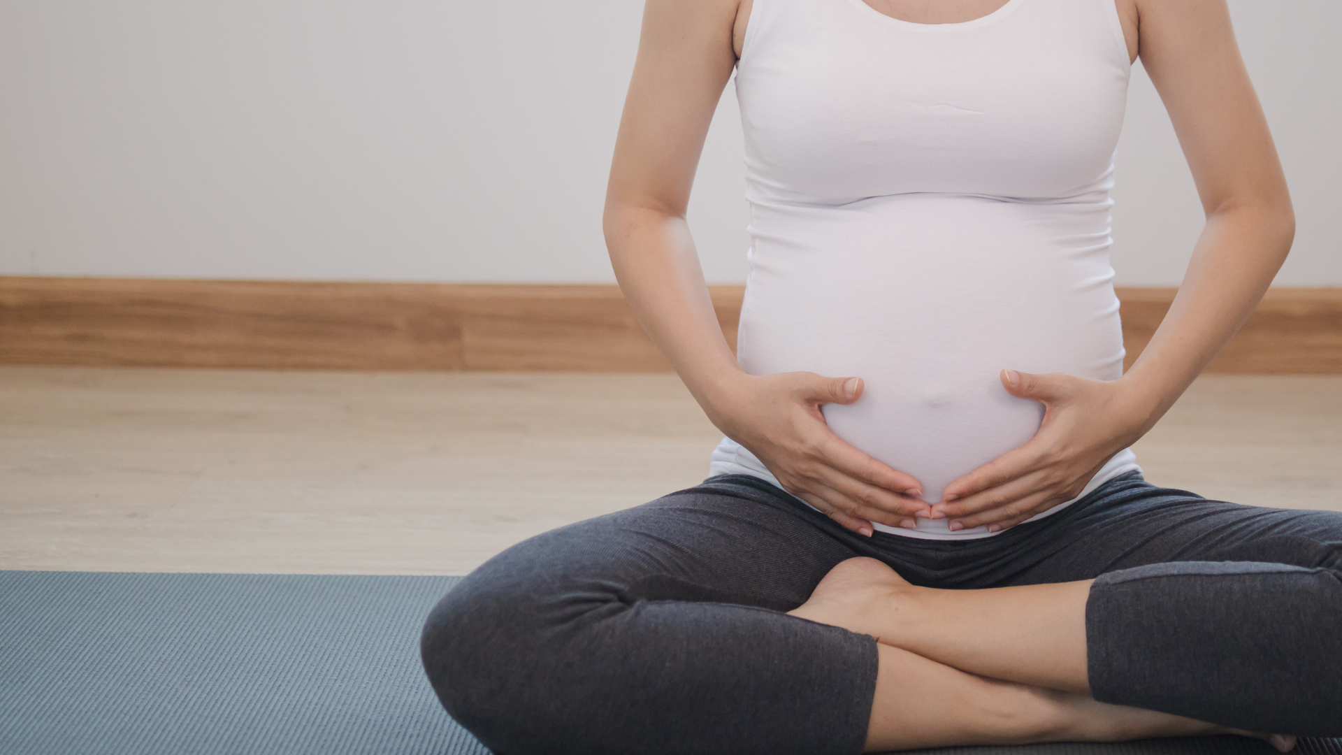 Calm pose young asian pregnant woman touching her belly and practice yoga in Lotus Pose. 