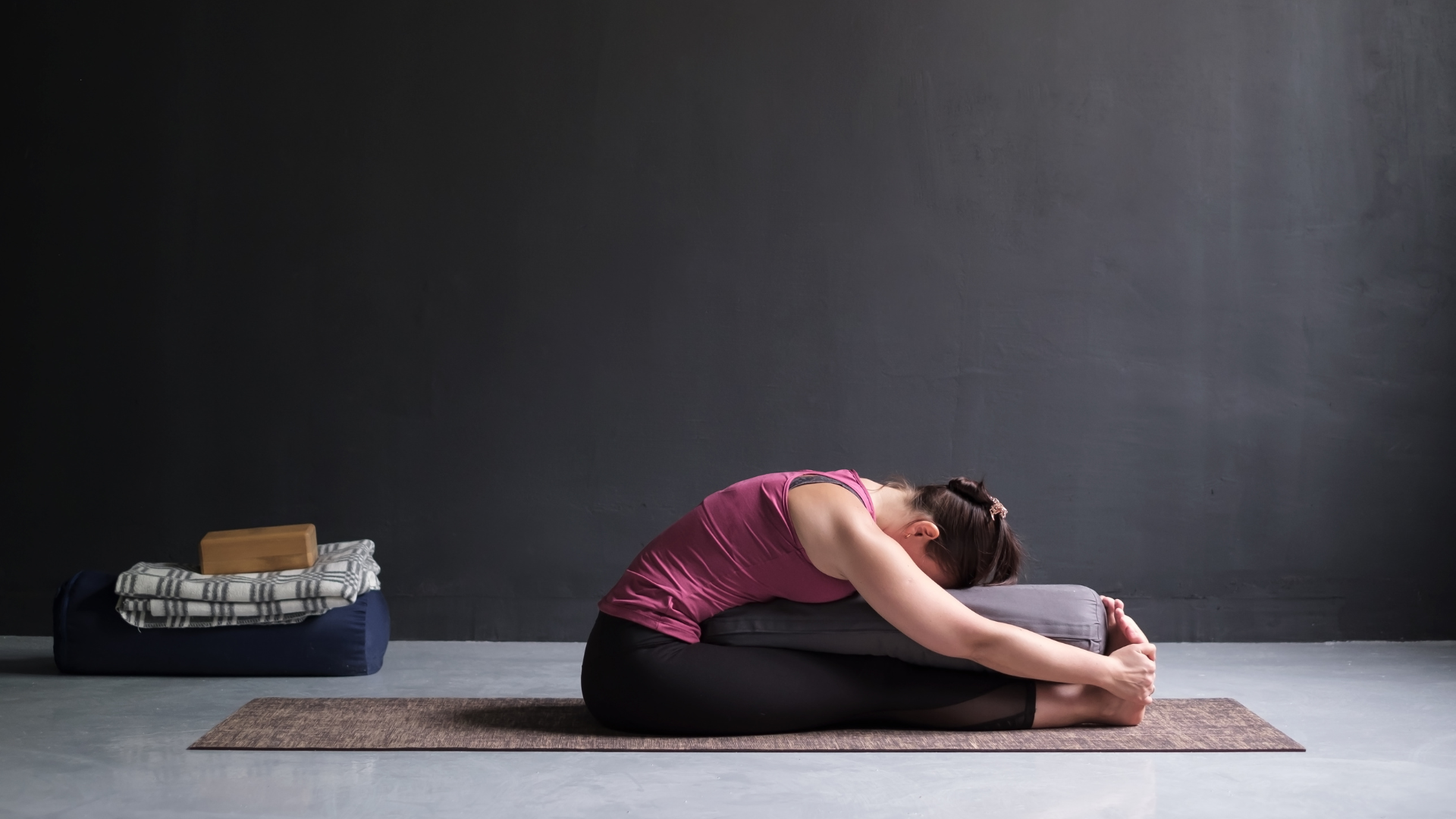 Young yogi practicing Yin yoga, and Paschimottanasana or Seated Forward Bend Pose to promote healthier fascia. 