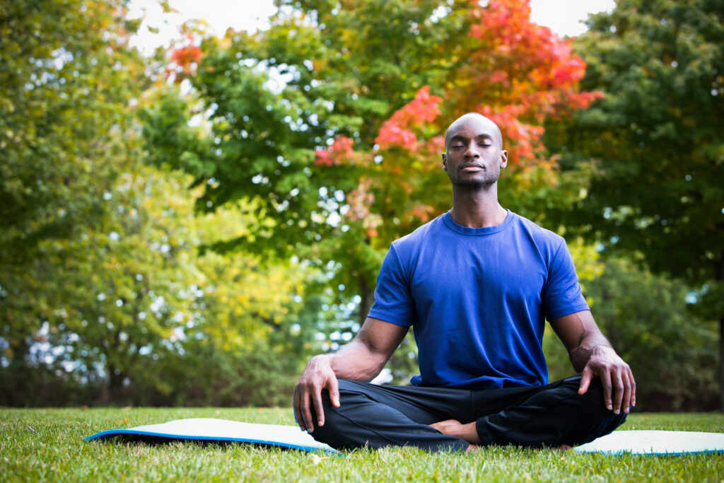 ypung man sitting outside in nature developing self awareness while in seated meditation.