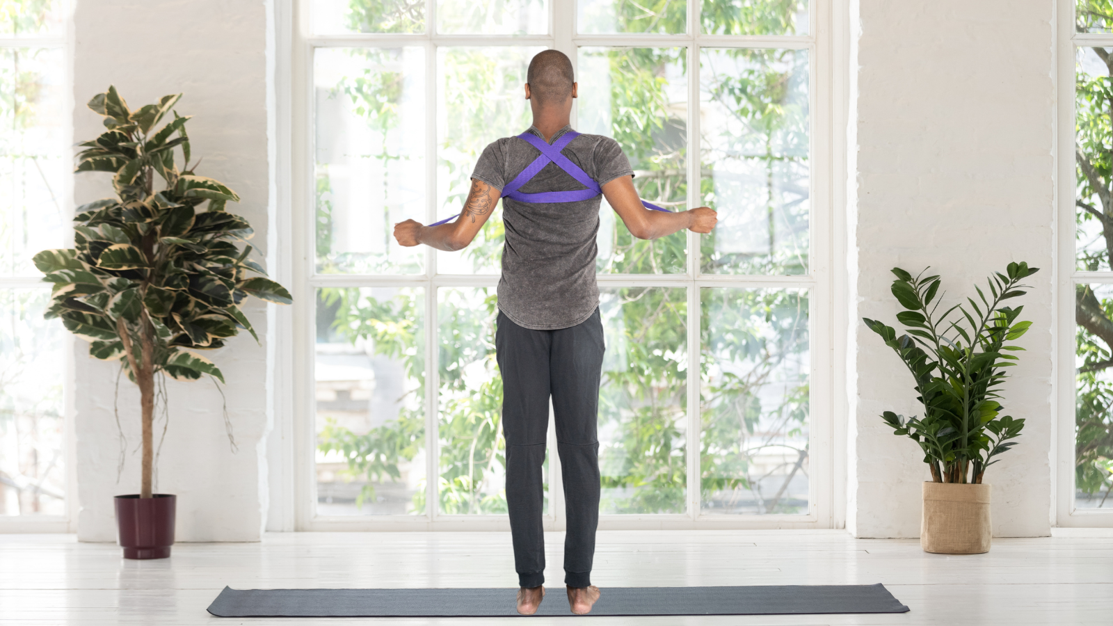 Image depicts a hack with yoga student using a strap to help retrain and improve posture.