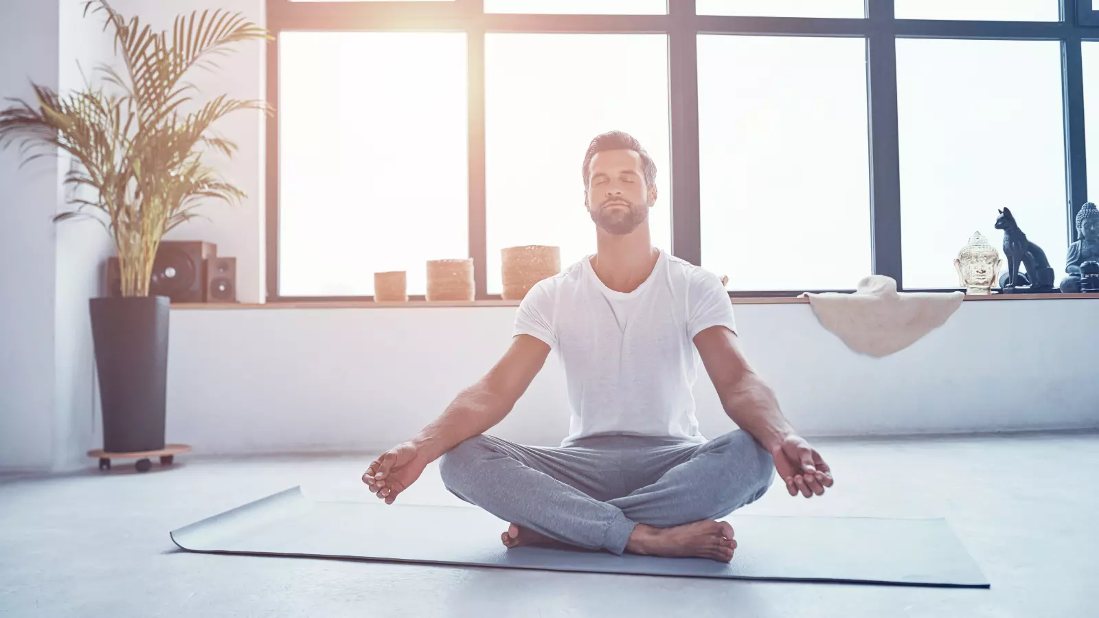  Handsome young man practicing meditation in his Yin yoga practice while sitting in lotus position.