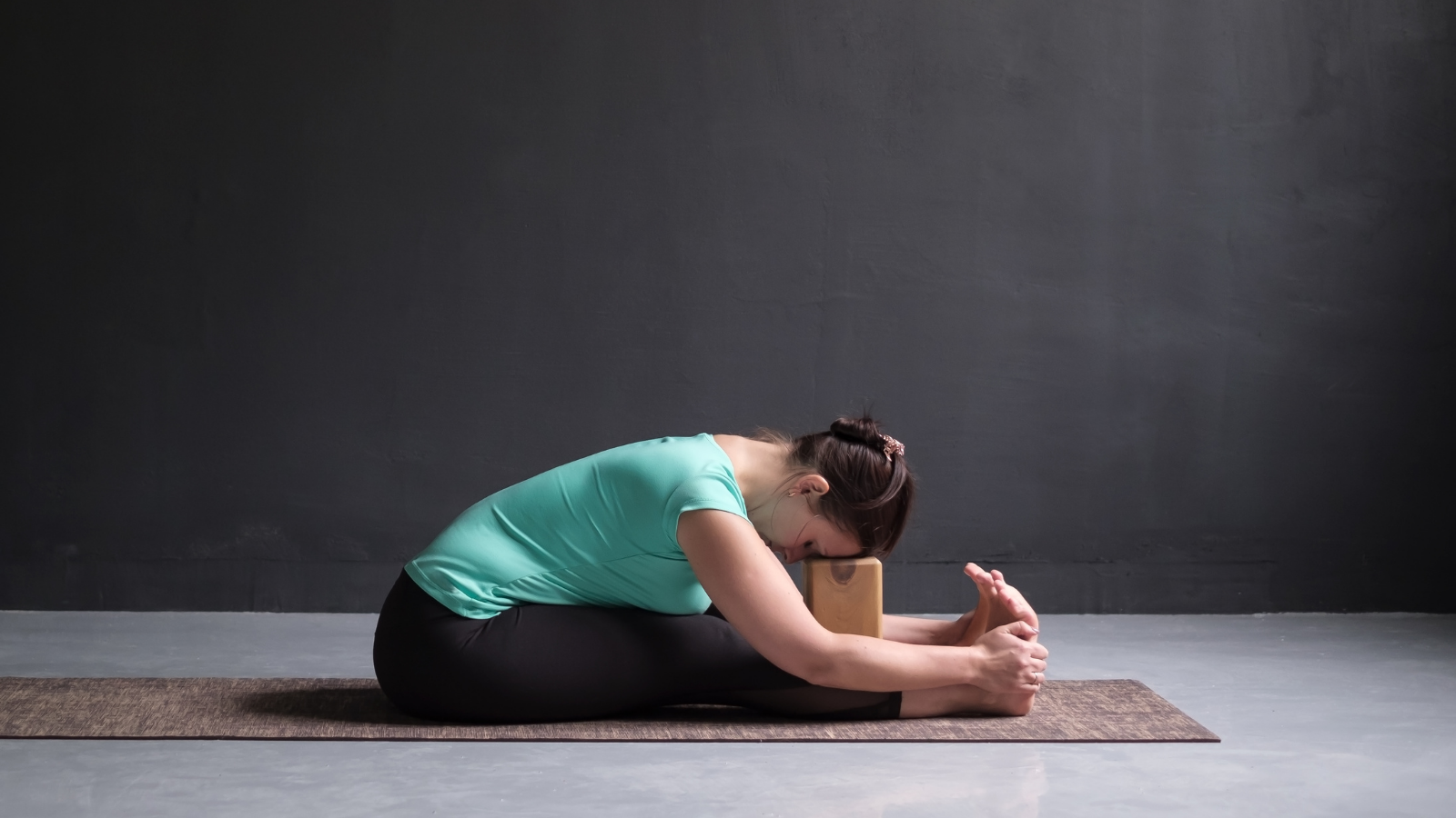 Young woman practicing yoga at home, doing Paschimottanasana Pose, Seated Forward Bend Pose