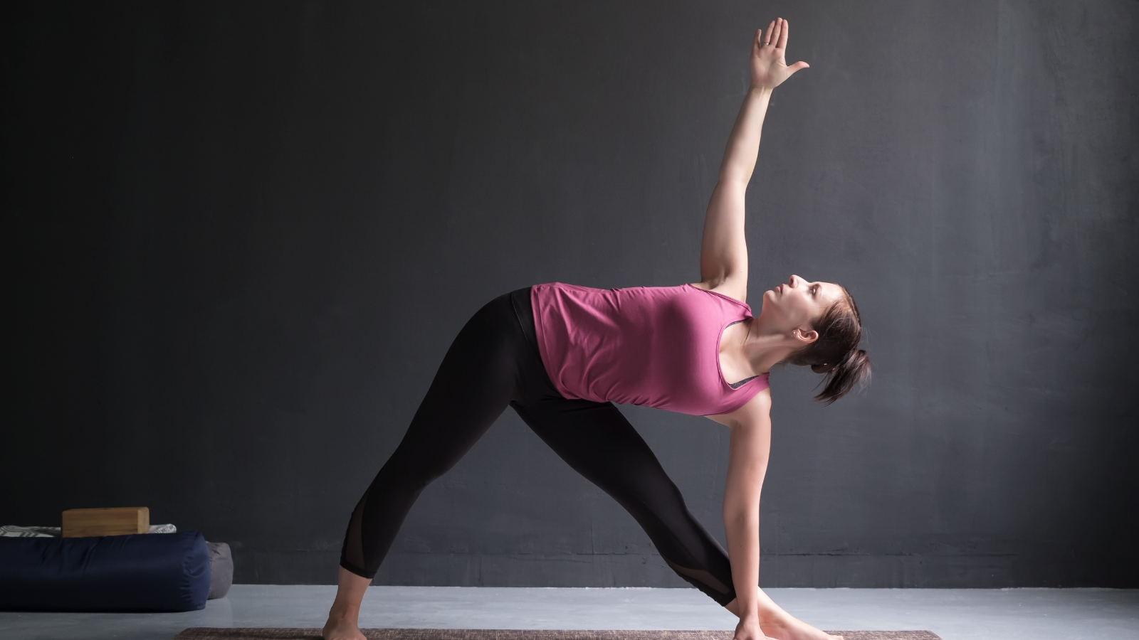 young woman working out doing yoga's Utthita Trikonasana, extended triangle pose