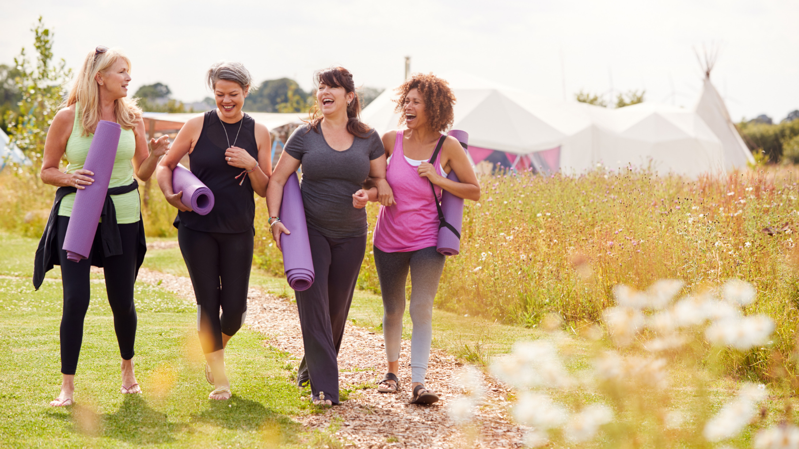 Group Of Mature Female Friends On Outdoor Yoga Retreat Walking Along Path Through Campsite to balance vata dosha