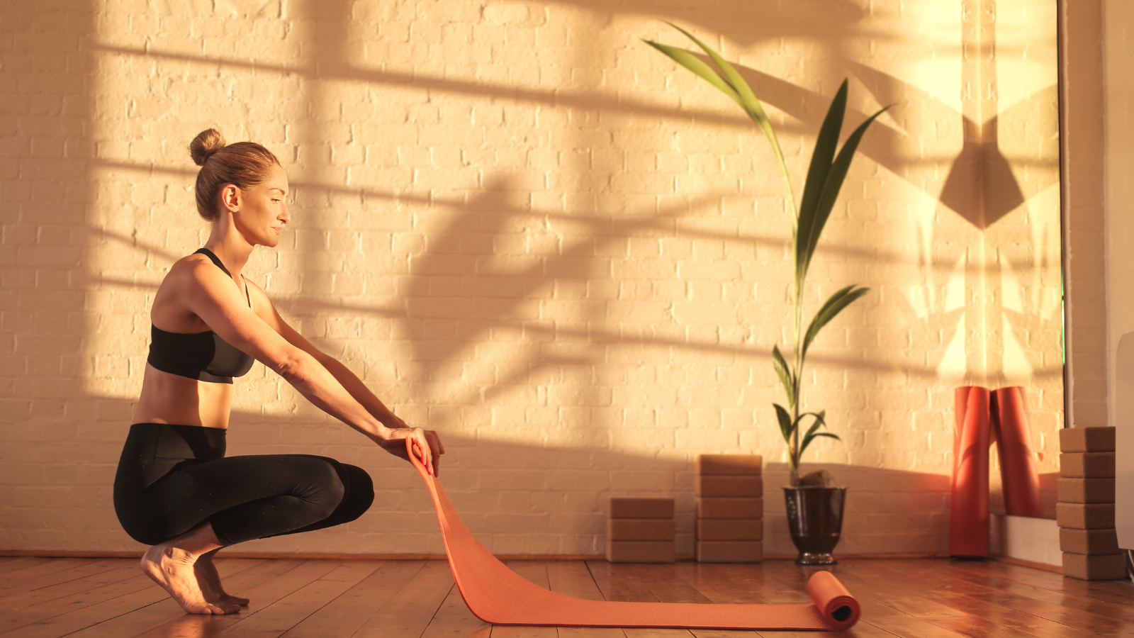 Woman preparing for doing yoga, lying down a mat on the floor