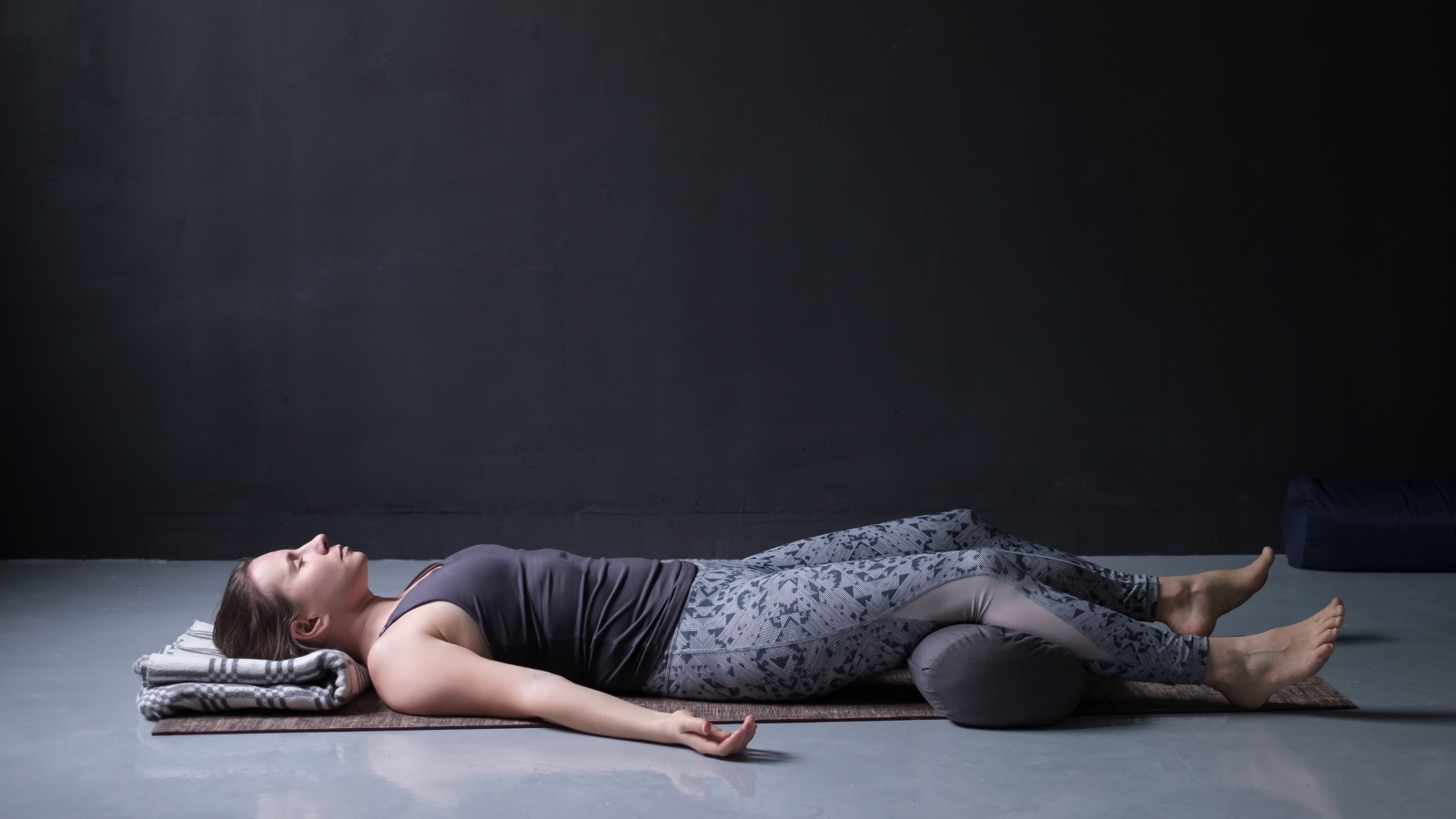 woman working out, doing yoga exercise on wooden floor, lying in Savasana or Corpse Pose, resting after practice