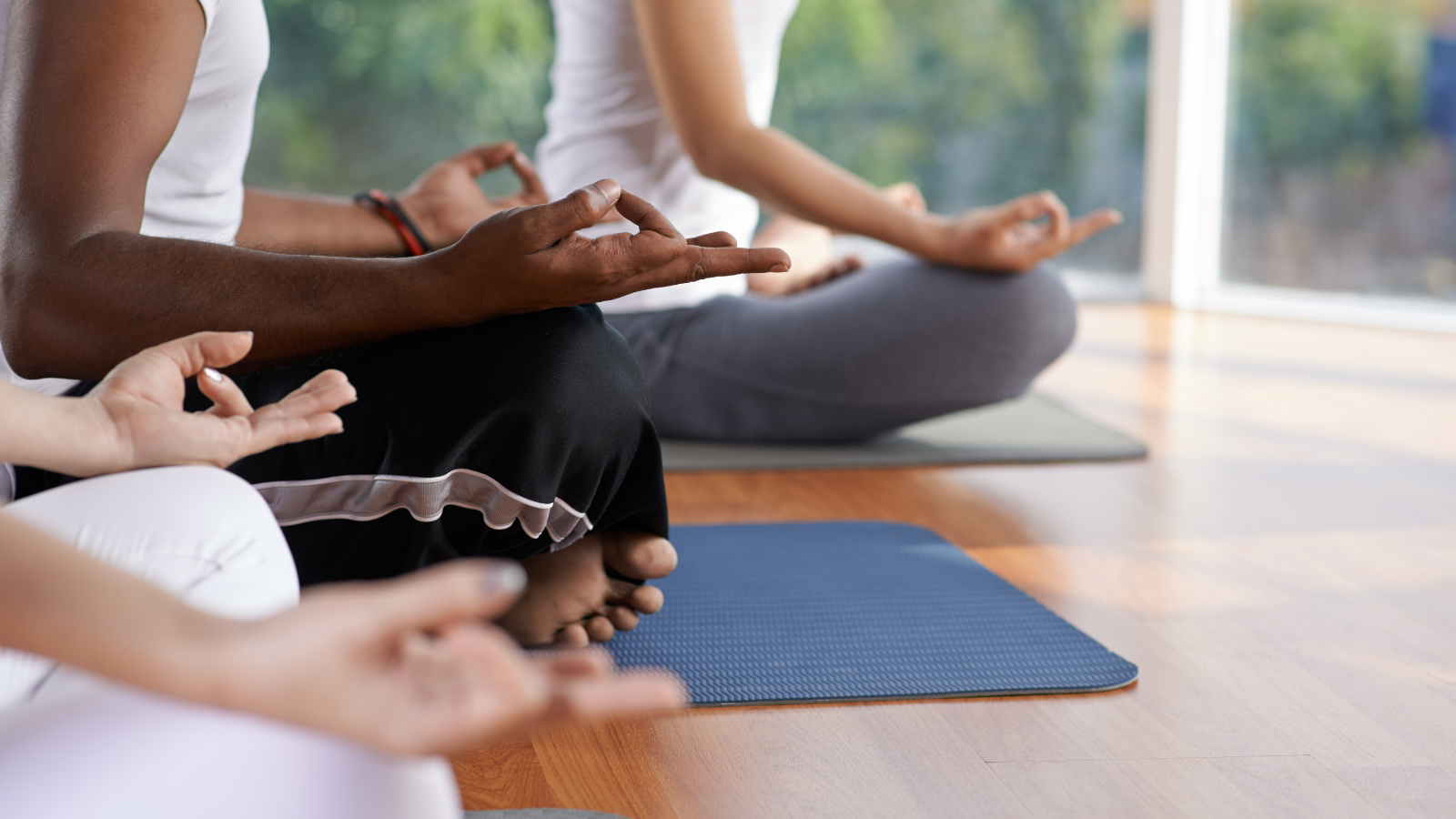 Cropped image of people meditating in lotus position. Title Text: How to meditate and breathe for improved health and wellbeing