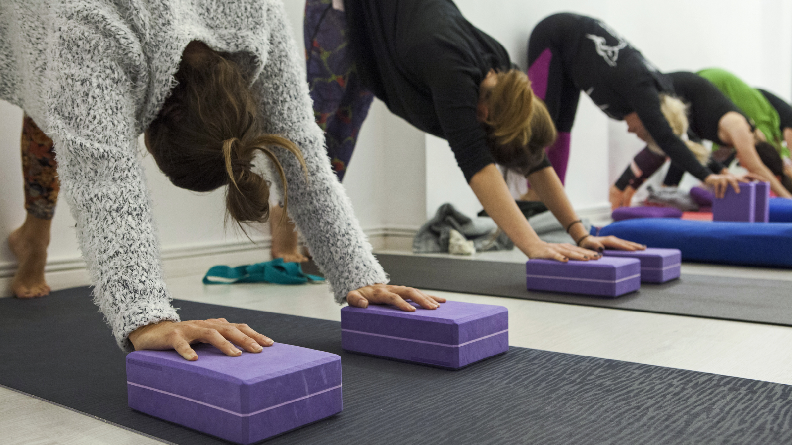 practicing yoga therapy, stretching in Down Dog Pose using blocks and the wall