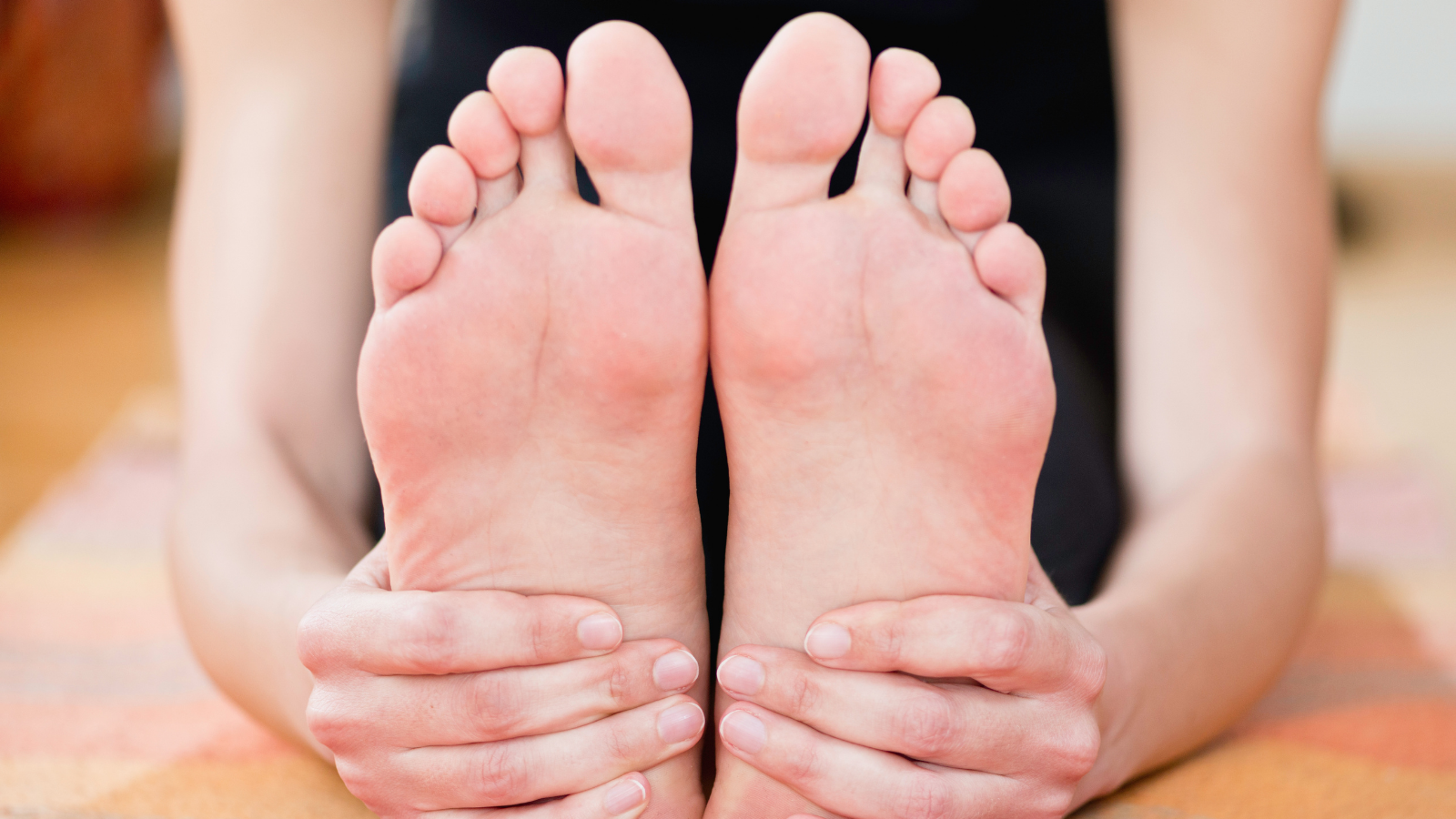 Paschimottanasana or seated forward bend yoga pose - holding feet detail.