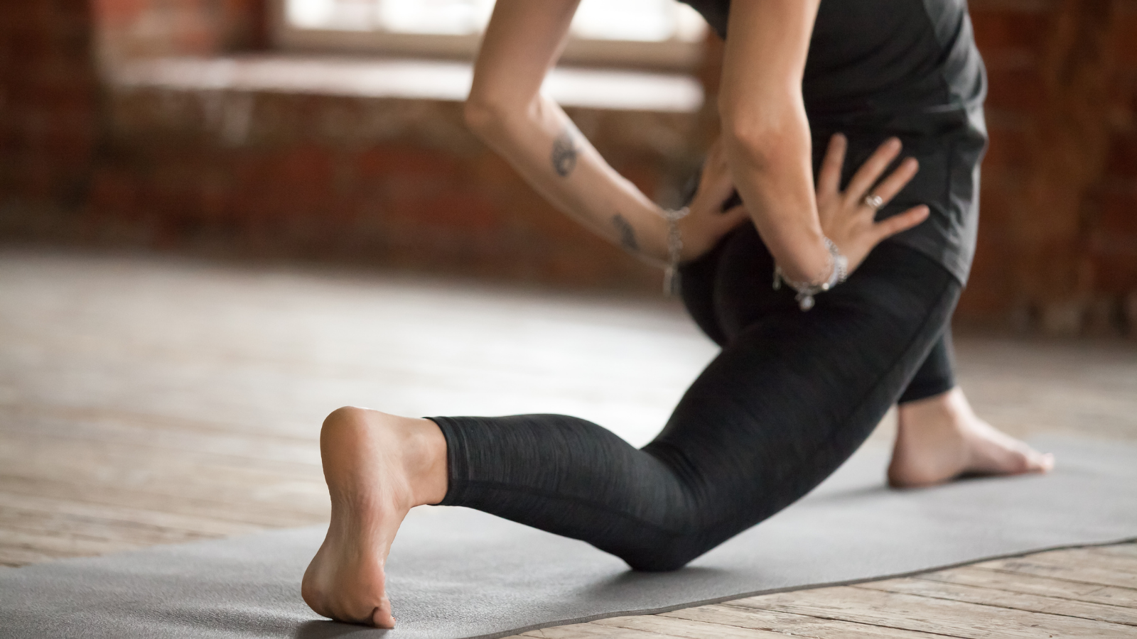 Young woman practicing yoga, doing Horse rider exercise, Anjaneyasana Pose, also called Crescent Lunge variation. 