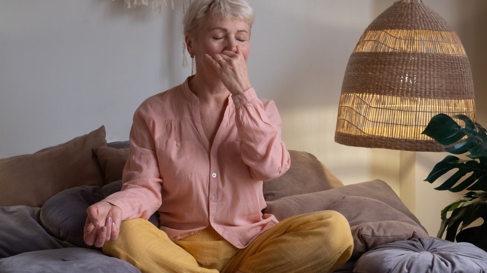 Senior woman practicing yoga at home, making Alternate Nostril Breathing exercise or Nadi Shodhana pranayama