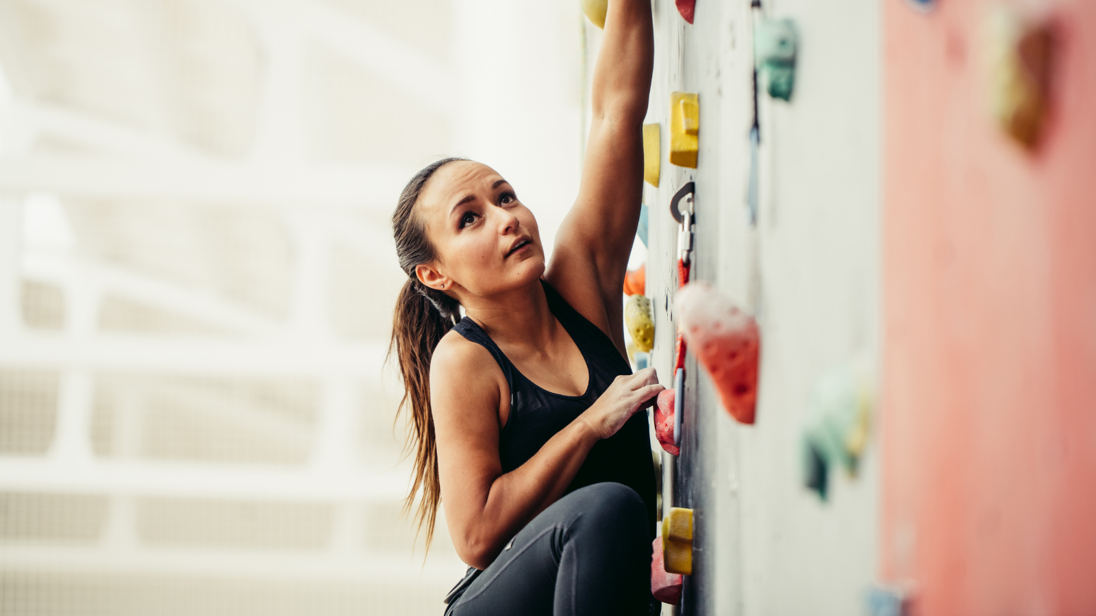 Cropped view of a fit business woman, climbing on a rock wall.