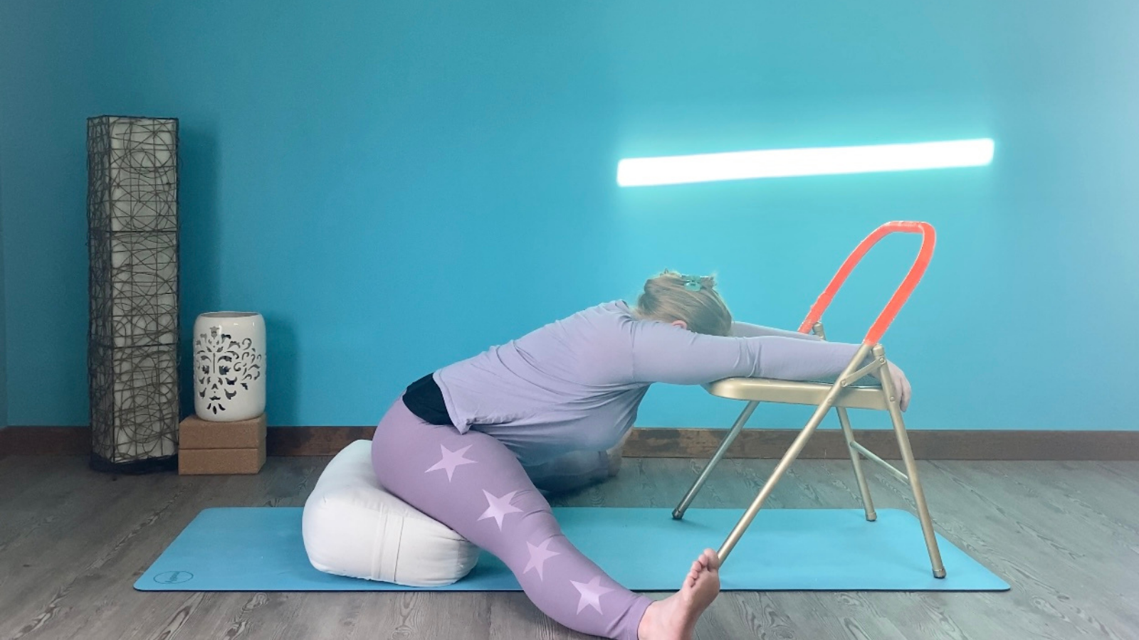 Restorative Upavistha Konasana using a chair and bolster for support.