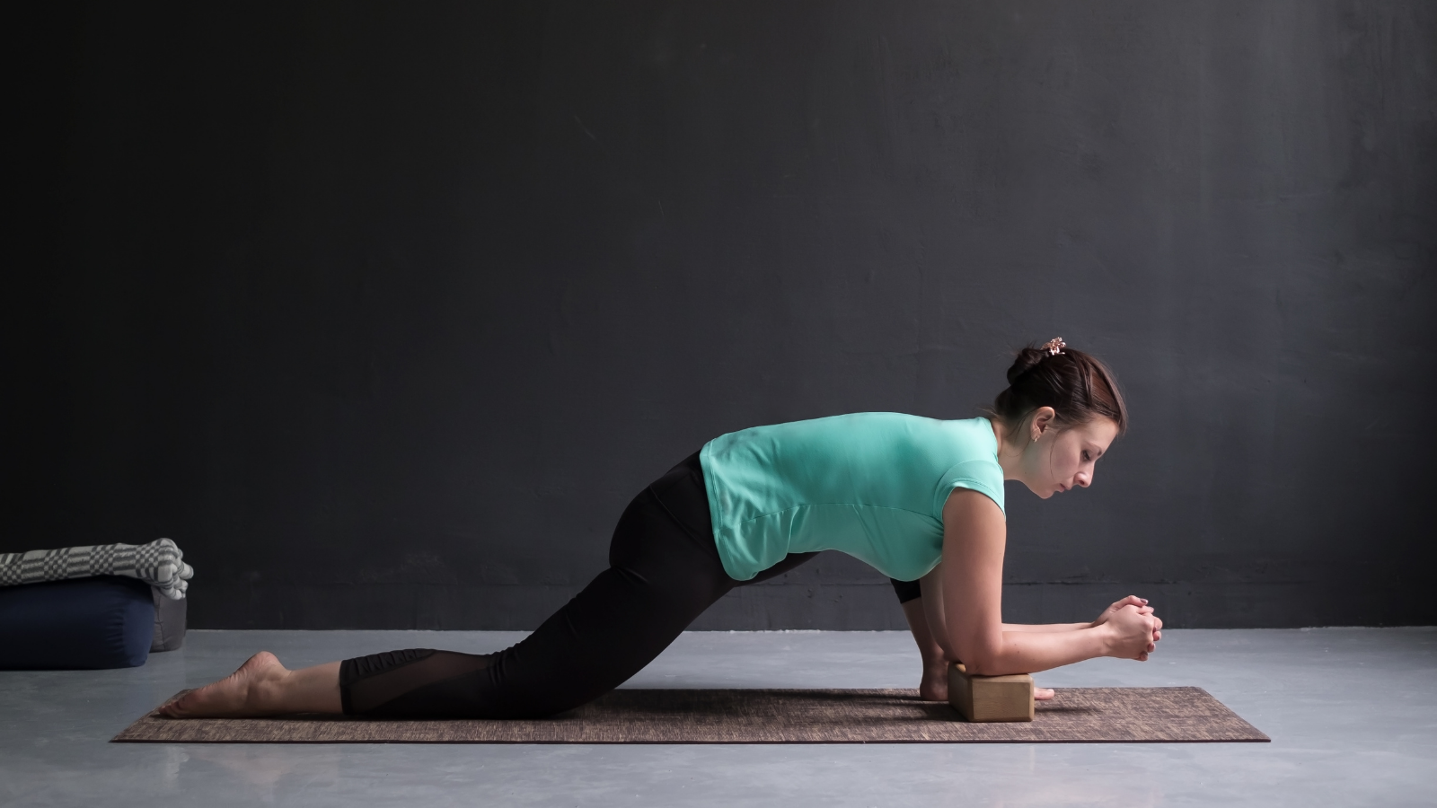 Young slim girl, practicing an Anjaneyasana Pose variation- full length side view.