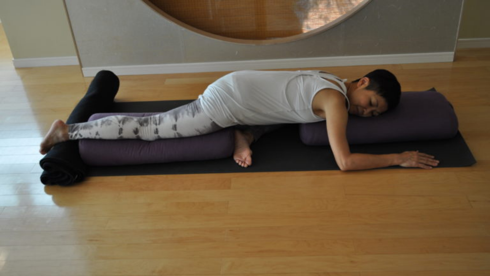 Image depicts a supported version of Pigeon Pose with props. 