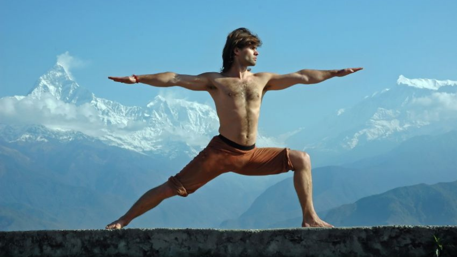 Image depicts Warrior ll pose or Virabhadrasana Pose practiced in a mountain setting. 