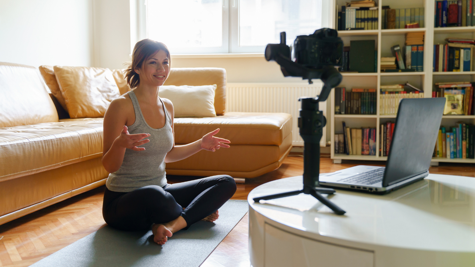 Young woman practicing yoga at home teaching online yoga class.