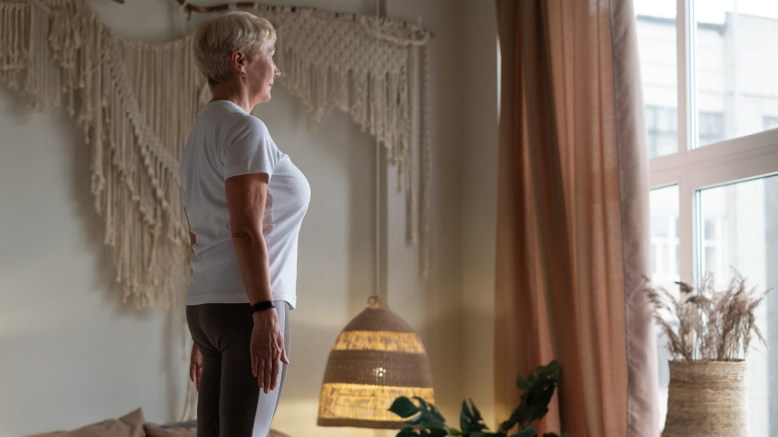 Senior woman working out indoors standing in Tadasana, Mountain Pose.