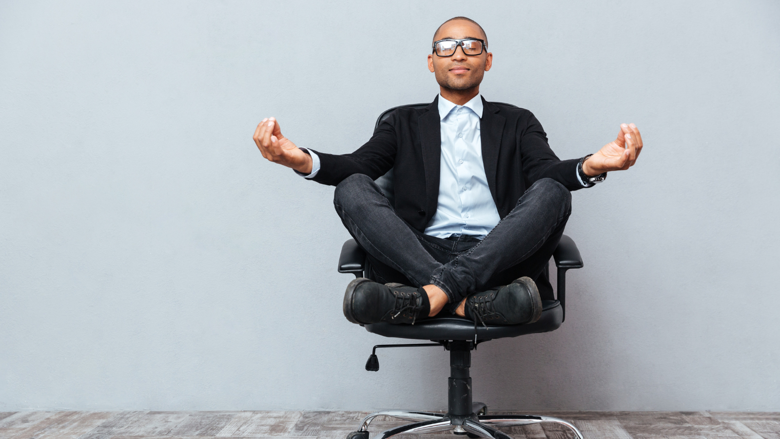 Relaxed handsome young man sitting and meditating on office chair.