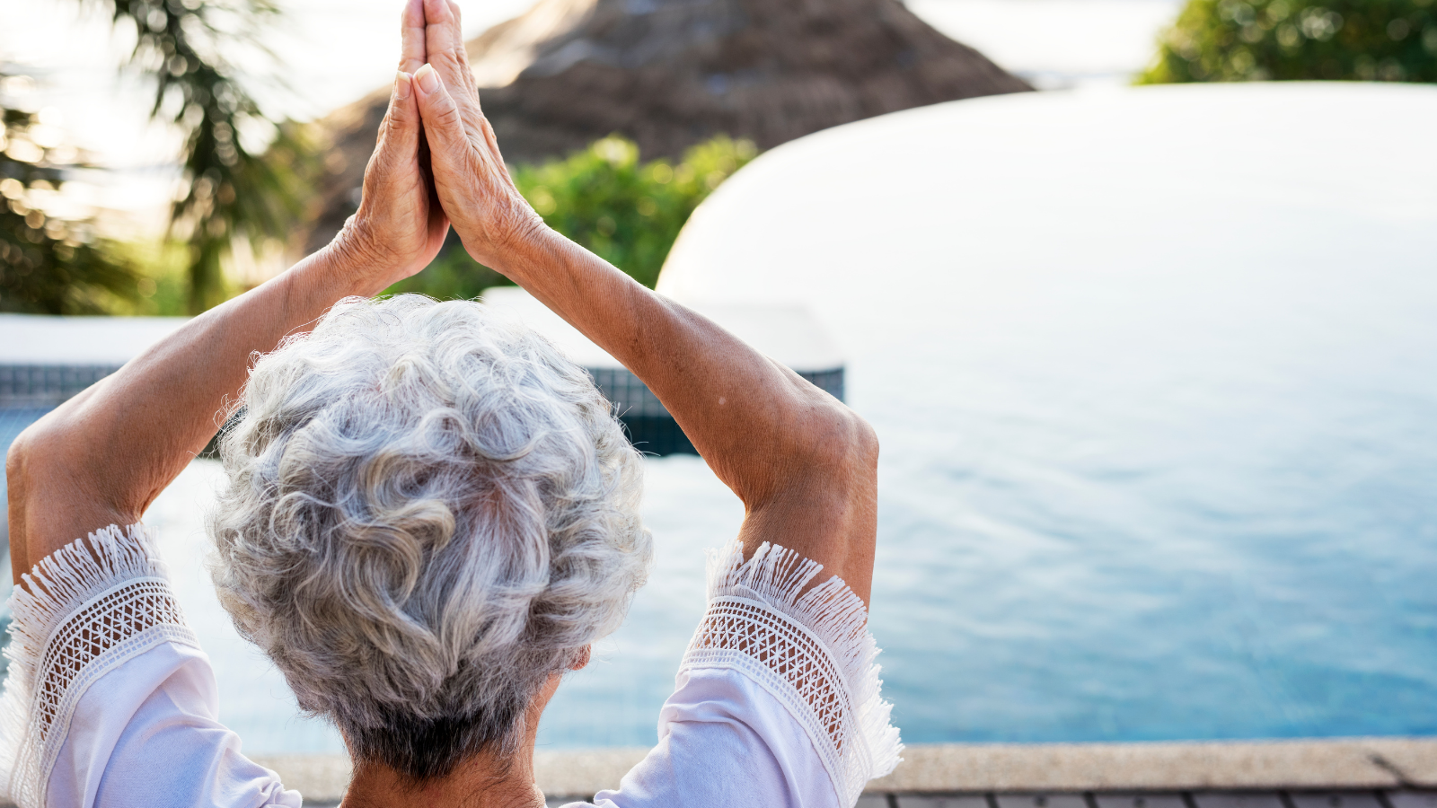 Senior adult practicing yoga by the pool.