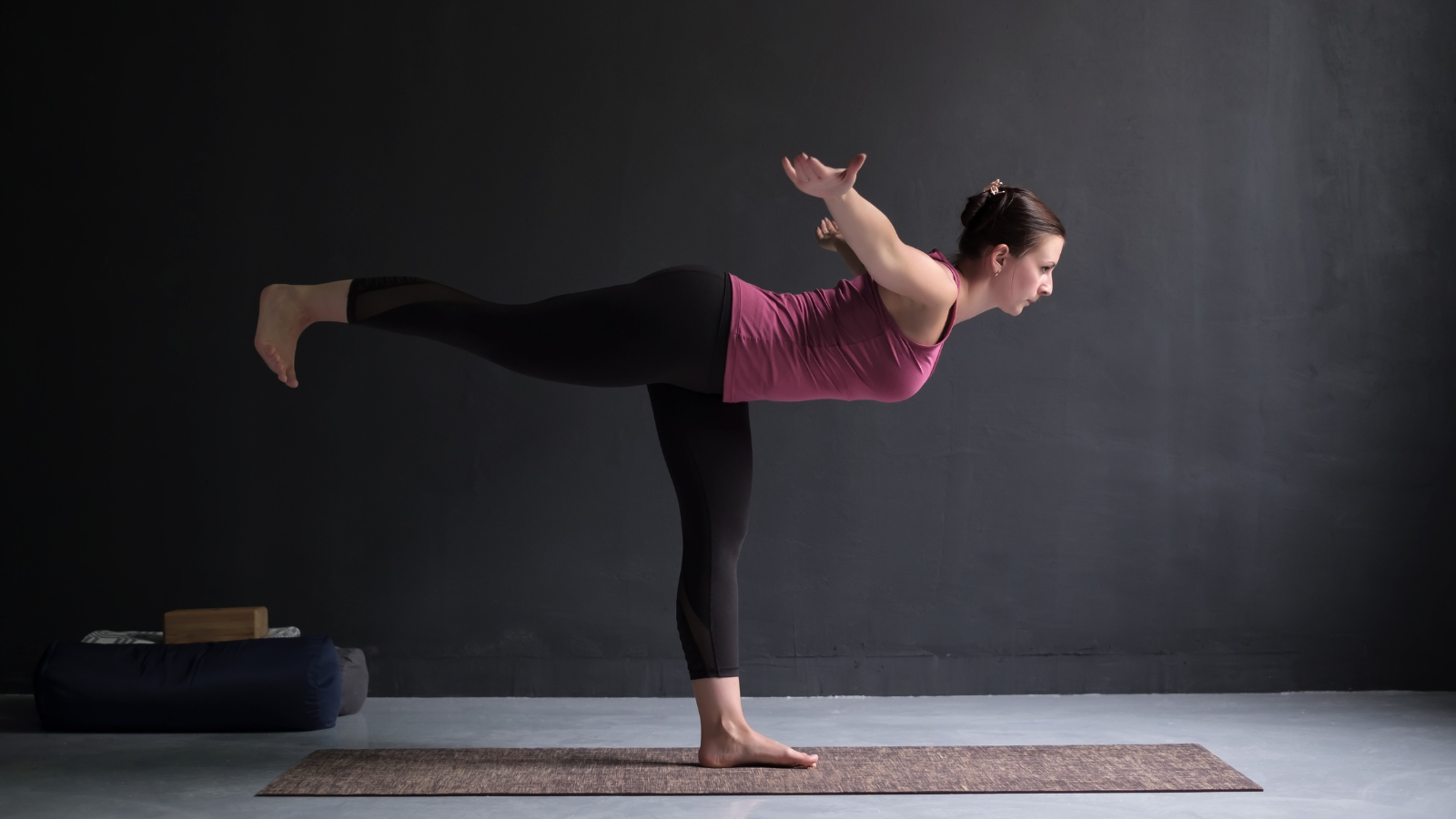 Young sporty attractive woman practicing yoga, doing Warrior III exercise, or Virabhadrasana lll pose, indoor full length.